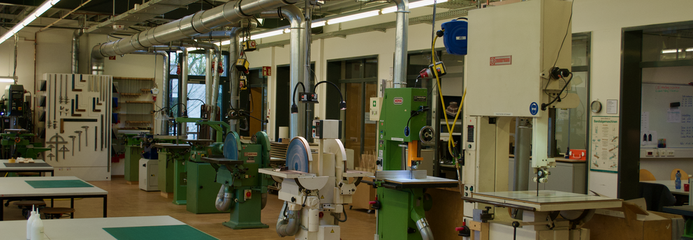 Zu sehen sind die Standmaschinen, mit denen Studierende nach Unterweisung arbeiten dürfen. Von rechts vorne nach hinten links: zwei Bandsägen, zwei Tellerschleifer und ein Bandschleifer.
